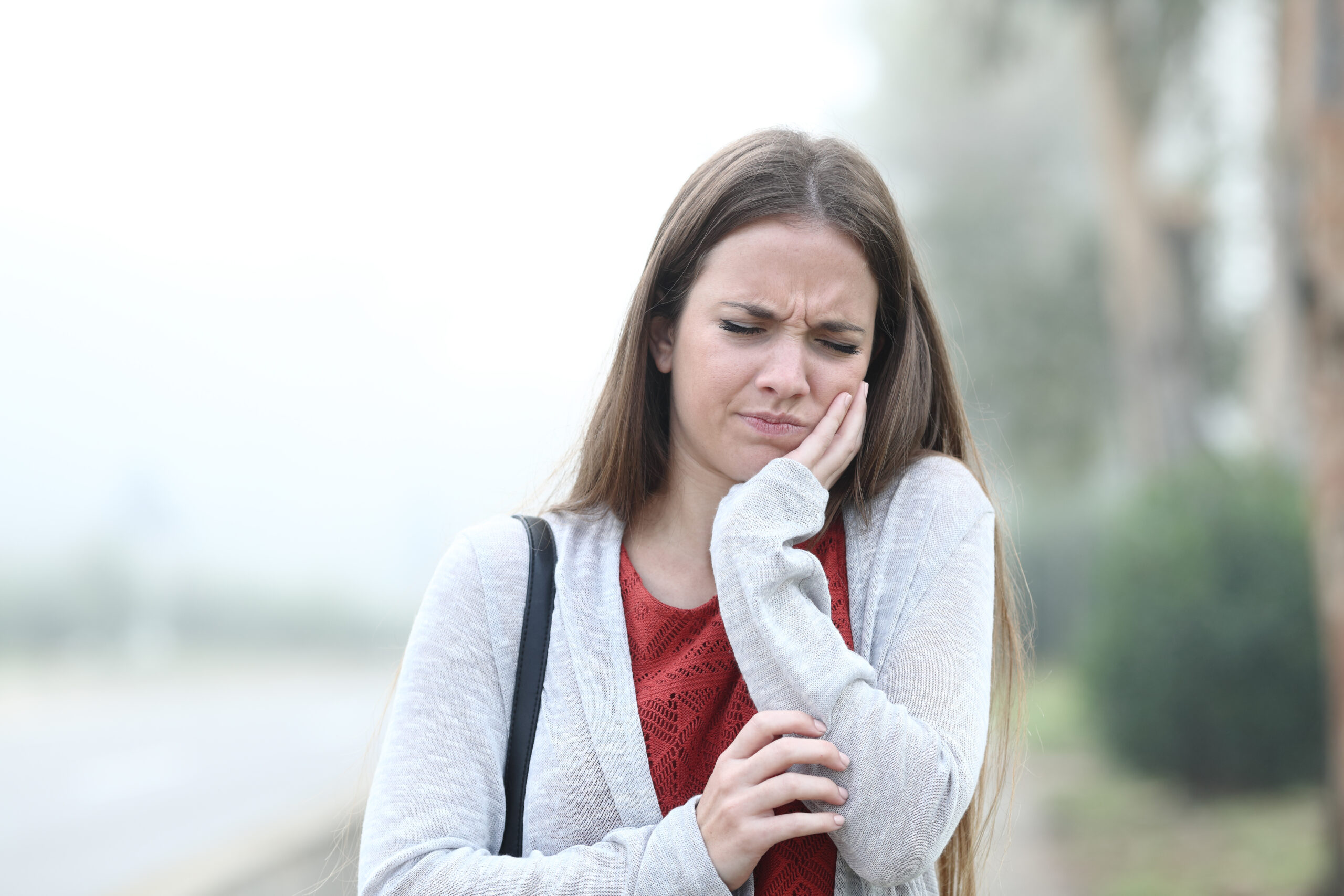 Front view portrait of an woman suffering tooth ache a foggy day