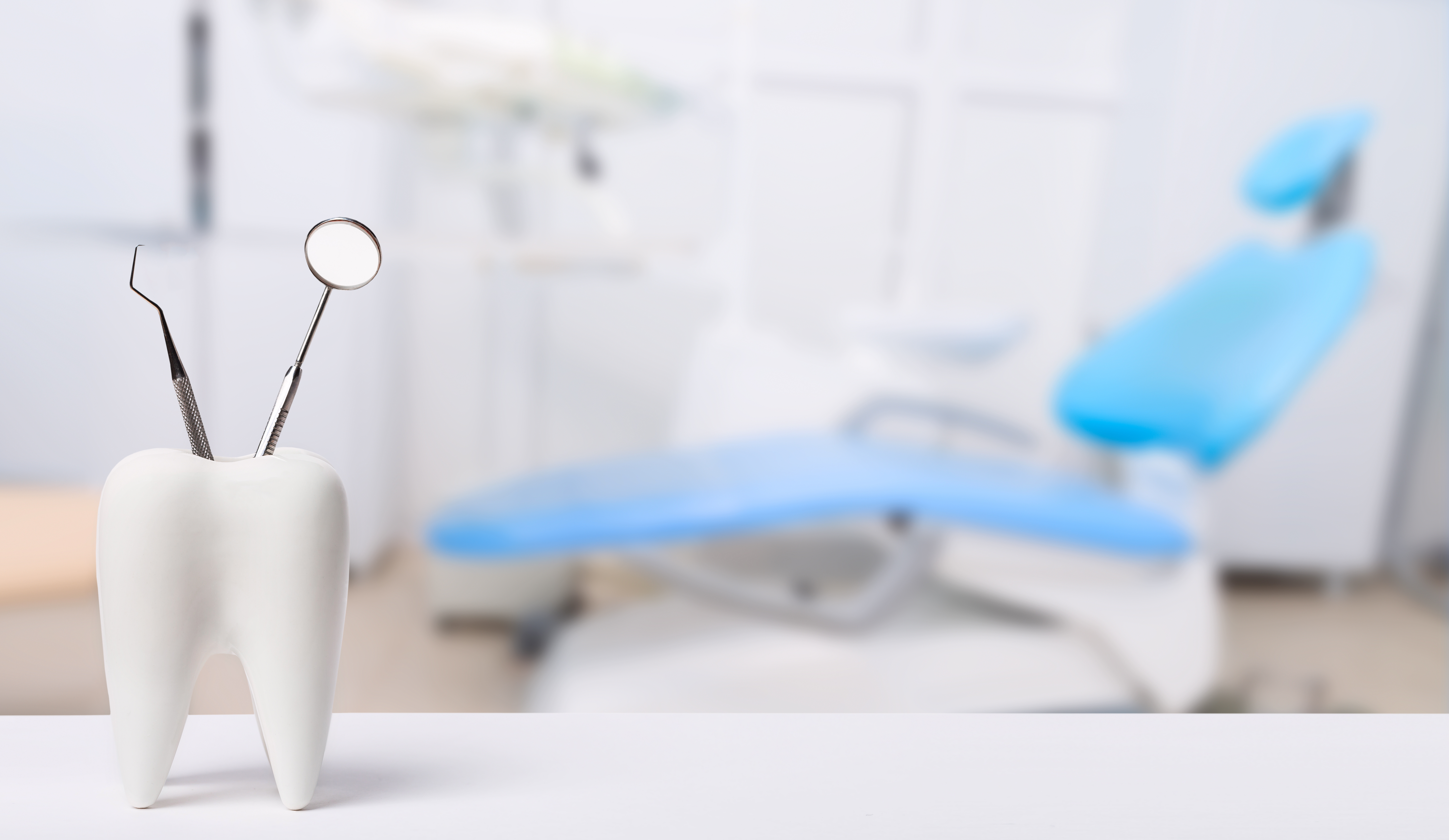 Dental mirror and probe tool beside a healthy white tooth in a dental office