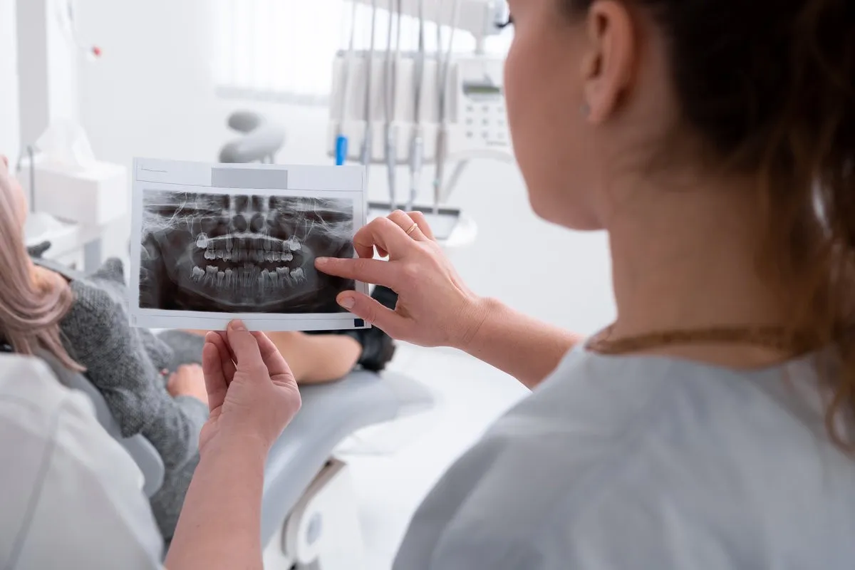 female dentist looks at an x-ray of the patient's teeth, doctor says which teeth to treat. Modern dental office. x-ray of the jaw